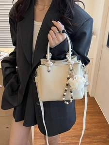 Chic cream beige leather bucket bag with knot handle and pompom charm for women