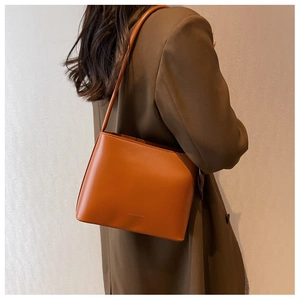 Vue latérale d'un sac bandoulière vintage marron-orange porté avec un blazer marron chic