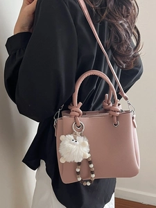 Pink lychee texture tote bag with knot handle and plush monster charm shown on model