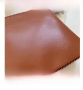 Gros plan du sac en cuir marron mat montrant le logo embossé et les coutures de qualité