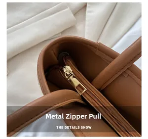 Close-up of the high-quality gold metal hardware zipper on a brown leather tote bag