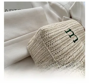 Close-up of woven straw bag showing stitching and green embroidered letter B detail