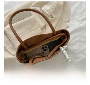 Top view of brown leather tote interior holding phone and wallet with silk scarf detail