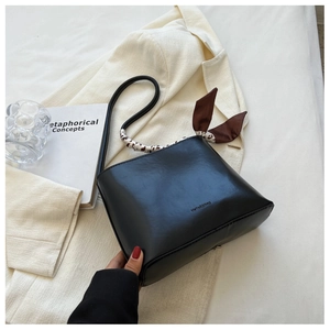 Détail d'un sac à main en cuir noir avec foulard imprimé animal et nœud sur l'anse