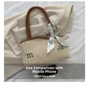 Detail of straw tote bag showing woven texture, silk scarf handle, and phone size comparison