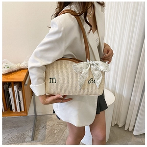 Detail of straw tote bag with brown leather straps and floral scarf accessory
