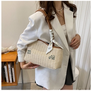 Détail du sac cabas en paille tissé avec bordure en cuir marron et foulard en soie