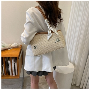 Détail du sac cabas en paille tissée avec bordure en cuir marron et foulard en soie