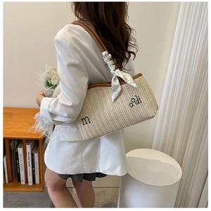Détail du sac cabas en paille tressée avec bordure en cuir marron et foulard en soie