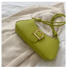 Detail of green leather underarm bag featuring a gold buckle and knotted strap design