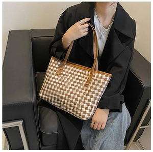 Detail der karierten Shopper-Tasche mit braunen Lederriemen und goldfarbenen Metallnieten