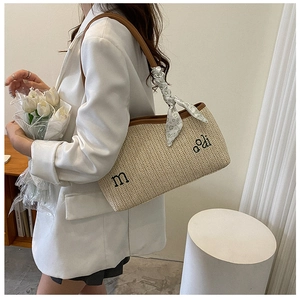 Détail du sac cabas en paille tressée avec lanières en cuir marron et foulard en soie fleuri