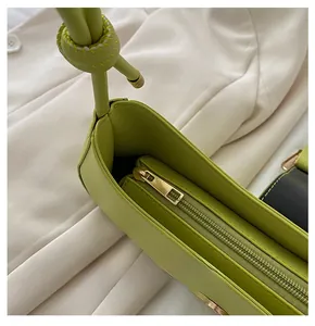Detail of smooth gold metal zipper and stitching on green leather underarm bag