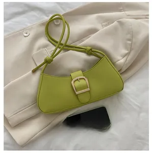 Detail of green hobo bag featuring a gold buckle and shoulder strap over a beige blazer