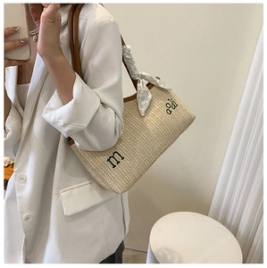 Détail du sac cabas en paille tissée avec poignées en cuir et foulard décoratif en soie
