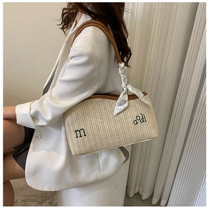 Détail du sac cabas en paille tressée beige avec broderie verte et foulard sur la poignée
