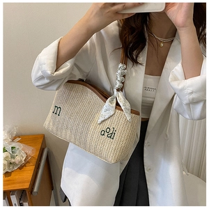 Détail d'un sac cabas en paille tressée avec broderie verte et foulard en soie décoratif