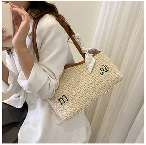 Détail du sac cabas en paille tissée avec bordure en cuir marron et foulard en soie fleuri