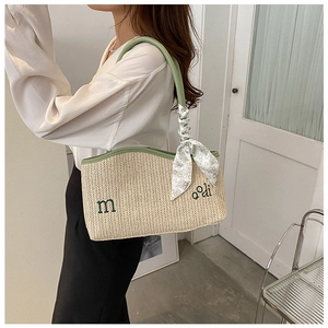 Détail du sac en paille tissé avec bordure en cuir vert et foulard à fleurs