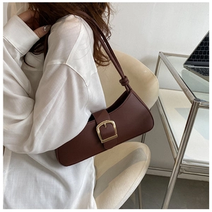 Close-up of brown leather underarm bag with gold metal buckle and knotted strap detail