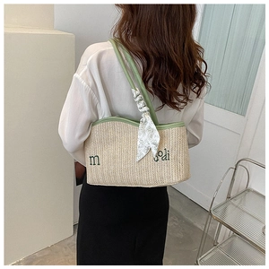 Detail of straw woven tote bag with green leather trim and floral scarf decoration