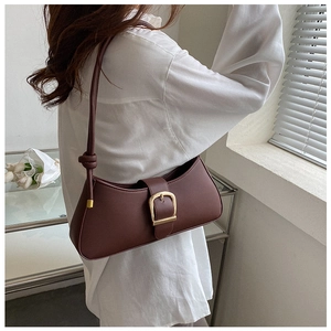Close-up of a vintage dark brown leather underarm bag with a gold horseshoe buckle