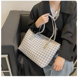 Detail der karierten Shopper-Tasche mit Hahnentrittmuster und Lederriemen mit Nieten