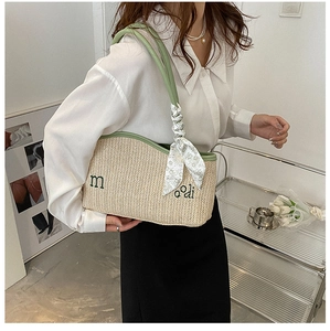 Detail of straw shoulder bag with green leather trim, embroidery and floral scarf