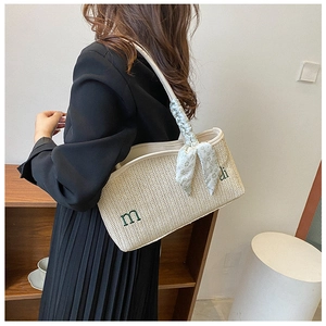 Detail of woven straw tote with green embroidery and floral scarf on strap