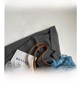 Close-up of blue woven tote bag featuring fringe details and premium leather shoulder strap