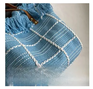 Macro shot of blue and white woven fabric texture with fringe detail and leather strap