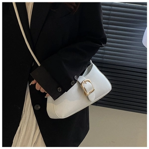 Detail of a white leather underarm bag with a gold horseshoe buckle on a black suit