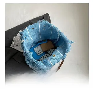 Top view of blue knit tote bag interior with tassel detail, fitting phone and wallet