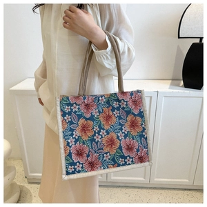 Detail of floral embroidered linen tote bag showing thick rope handles and texture