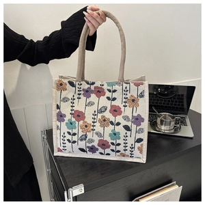 Detalle de bolso tote de lona con bordado floral colorido y asas trenzadas suaves