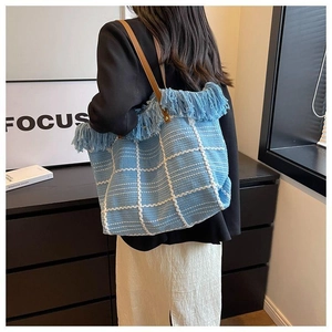 Detailed view of the woven blue checkered tote bag with fringe edge and leather straps