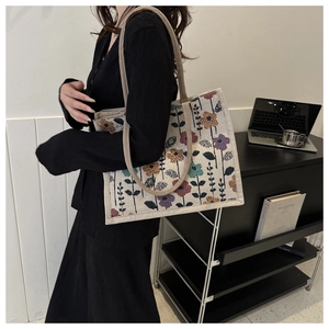 Detail view of cream canvas tote bag with vintage floral pattern worn over the shoulder