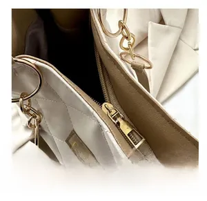 Close-up of smooth gold zipper and beige quilted leather texture on tote bag
