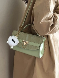Chique lichtgroene crossbodytas met gouden slot en pluchen hanger op modeloutfit