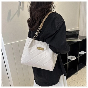 Detail of off-white quilted tote bag with gold chain strap worn by a female model