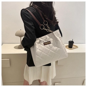 Close-up of beige quilted tote bag with diamond pattern and gold-tone hardware