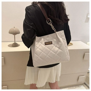 Detail of off-white quilted tote bag featuring gold chain strap and fashion label