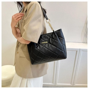 Close-up of black quilted tote bag with diamond stitching and gold chain link details
