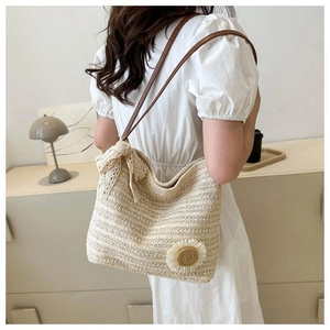 Detail view of woven straw tote bag featuring lace bow and handmade floral accents