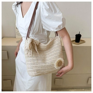 Detail of hand-woven straw tote with elegant lace bow and sunflower floral accents