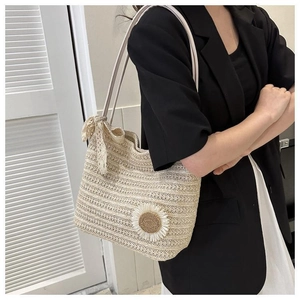 Detail of woven straw tote bag featuring white daisy flower and lace bow on shoulder strap