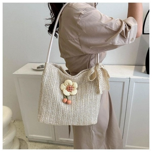 Detail of hand-woven straw tote bag featuring floral accents and lace ribbon strap
