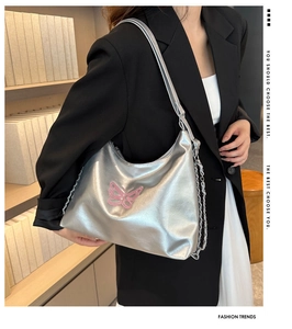 Detail of silver metallic bucket bag with pink butterfly embroidery and chain strap