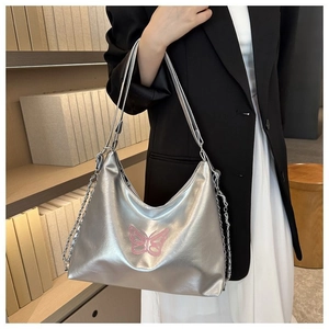 Detail of silver metallic shoulder bag featuring pink butterfly embroidery and chain strap