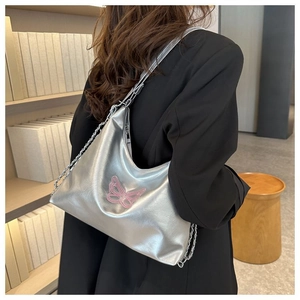 Silver metallic shoulder bag with pink butterfly embroidery and chain strap on a model